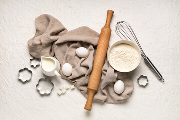 Composition with wooden rolling pin, kitchen utensils and ingredients for dough on white background