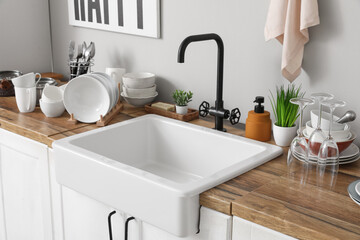 Stylish ceramic sink and clean dishes on wooden kitchen counter