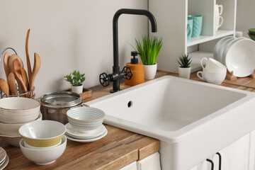 Fototapeta premium Stylish ceramic sink and clean dishes on wooden kitchen counter