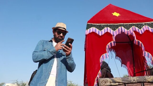 Indian man tourist searching location on smart phone or booking hotel online wearing hat and sunglasses enjoy holiday in rajasthan, Summer vacation, India tourism, 5G network, Wireless Technology.