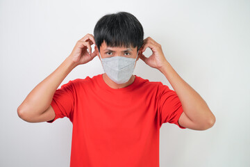 Young asian man in red wearing medical mask during virus outbreaks pandemic, isolated over white background.