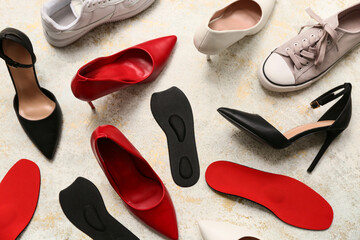 Different shoes with orthopedic insoles on light background