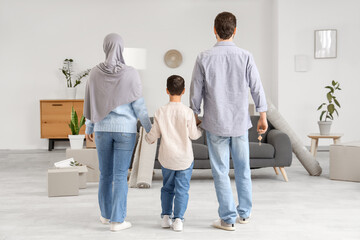 Fototapeta premium Happy Muslim family walking in their new house, back view