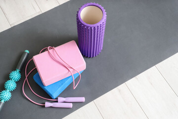 Sports equipment with foam roller, yoga blocks on mat in room. Closeup