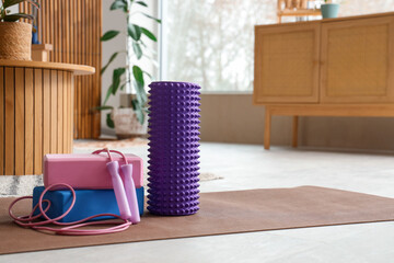 Foam roller with blocks and skipping rope on mat in living room