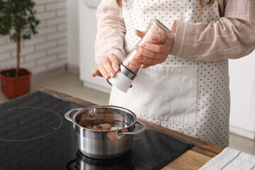 Woman boiling quail eggs in saucepot on stove