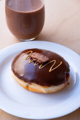 Iced Ring Doughnut on a White Plate Against a Wooden Background
