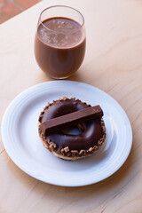 Iced Ring Doughnut on a White Plate Against a Wooden Background