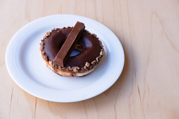 Iced Ring Doughnut on a White Plate Against a Wooden Background