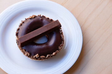Iced Ring Doughnut on a White Plate Against a Wooden Background