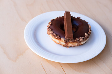 Iced Ring Doughnut on a White Plate Against a Wooden Background