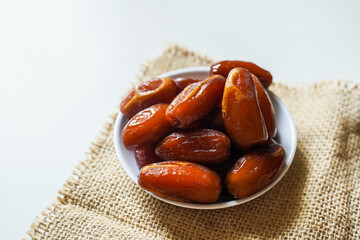 Dates fruit in small white bowl isolated on white background. (Kurma)