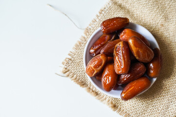 Dates fruit in small white bowl isolated on white background. (Kurma)