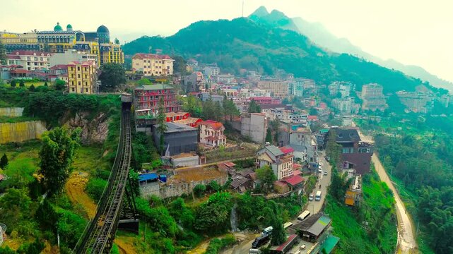 Panoramic aerial drone footage of the town of Sapa, Vietnam, during sunrise along its natural mountains and colorful buildings.
