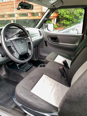 Interior of an Older Pickup Truck Showing Driver's Seat and Steering Wheel in a Rural Setting