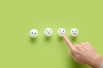 Man pointing at rating smiles on green background. Survey concept