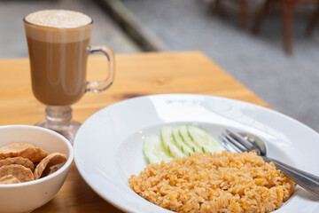 Fried Rice served in a bowl egg, vegetable, delicious thai dish like savory meal lunch. Plate of fried-rice cucumber as garnish, Asian cuisine nasi goreng a traditional indonesian breakfast or dinner.