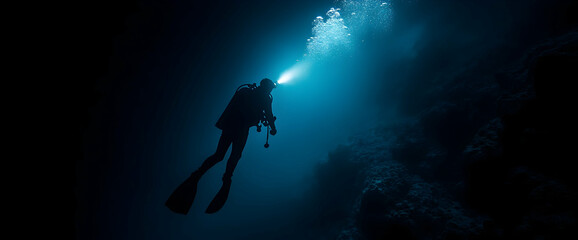 Solo diver explores dark ocean cave, light beam illuminates path