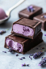 Dark chocolate bar with purple lavender caramel filling, elegant dessert. Open cut pieces in stack
