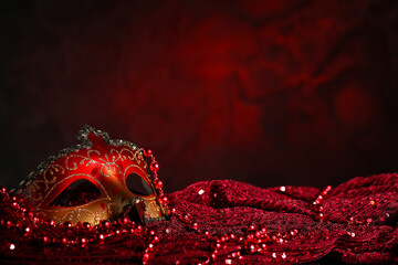 Beautiful carnival mask and beads on dark red background