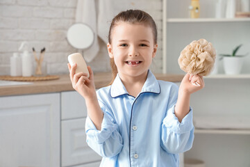 Cute little girl with soap bar and loofah in bathroom