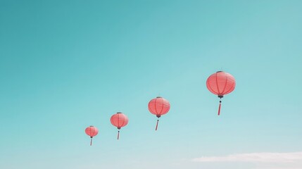 Obraz premium Four pink lanterns ascending against a clear blue sky.