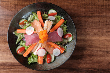 Mixed Vegetable Salad with Fish on a Black Plate