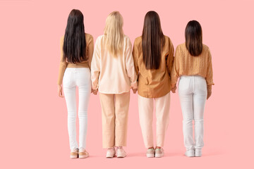 Naklejka premium Group of young women holding hands on pink background, back view. Women's History Month