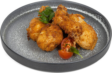 A plate of fried chicken wings and a tomato in black and white
