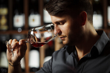 Bokal of red wine on background, male sommelier appreciating drink