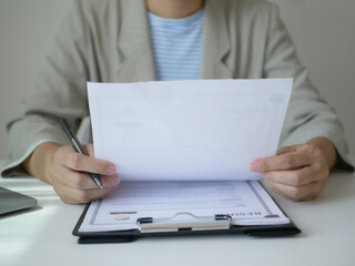 Young businesswoman holds a resume and evaluates it. Views the personal history of job applicants. Recruitment concept