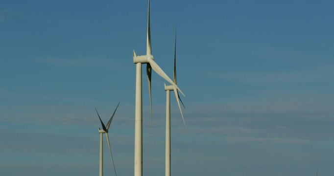 side on shot of wind turbines rotating with blue sky on the A A4061 at Hendre'r Mynydd Car Park,