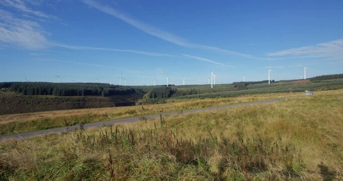 Extra Wide shot of wind turbines rotating with blue sky on the A A4061 at Hendre'r Mynydd Car Park,