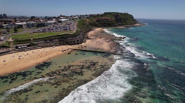 People At Sandy Bar Beach With Waves Splashing In Summer. New South Wales, Australia. aerial pullback shot