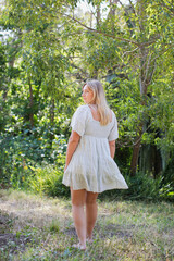 Girl in Sundress Walking in a green forest