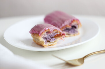 A cut blueberry eclair lies in a plate on a table