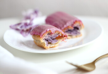 A cut blueberry eclair lies in a plate on a table