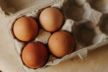 Overhead shot of four brown eggs in mostly empty egg carton