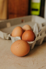 Close up shot of brown speckled egg sitting in front of egg carton