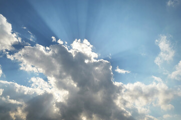 Blue sky with white clouds and sun bursting through