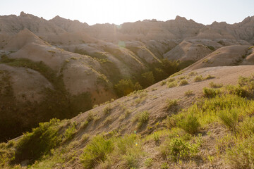 Sunlit Badlands landscape with rugged hills and green vegetation