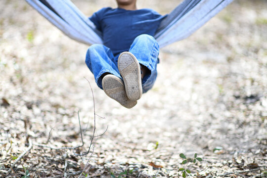 Child swinging in a hammock, legs raised playfully in motio