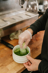 Barista whisking vibrant green matcha in a ceramic bowl at coffee shop