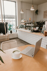 Matcha latte and laptop on wooden table in a bright modern cafe