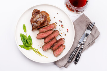 A perfectly cooked sliced striploin steak with a juicy, tender texture, served alongside a glass of rich red wine