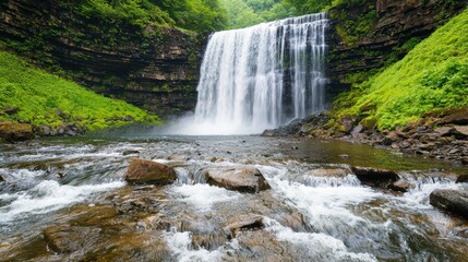 Obraz premium A stunning waterfall cascades over rocky terrain, surrounded by lush greenery, creating a serene and picturesque natural landscape.