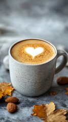 A cozy latte with a heart design, surrounded by autumn leaves and almonds.
