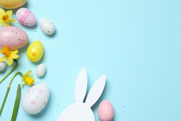 Happy Easter. Colorful eggs, bunny ears and yellow flowers on a pastel color background, space for text or advertising