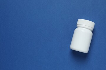 White bottle on blue background, top view