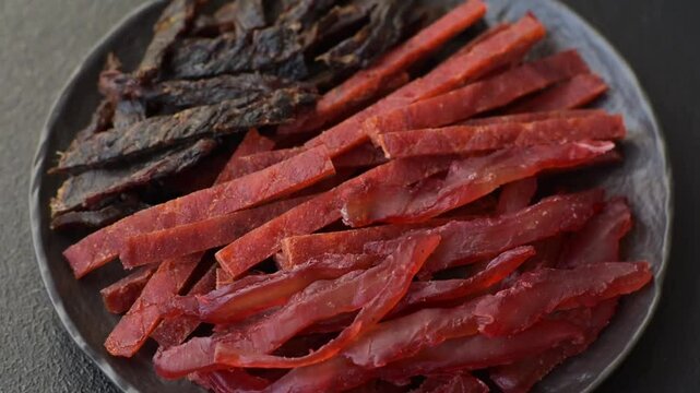 Jerky, dried fish in the form of sticks with salt, spices and herbs on a dark concrete background